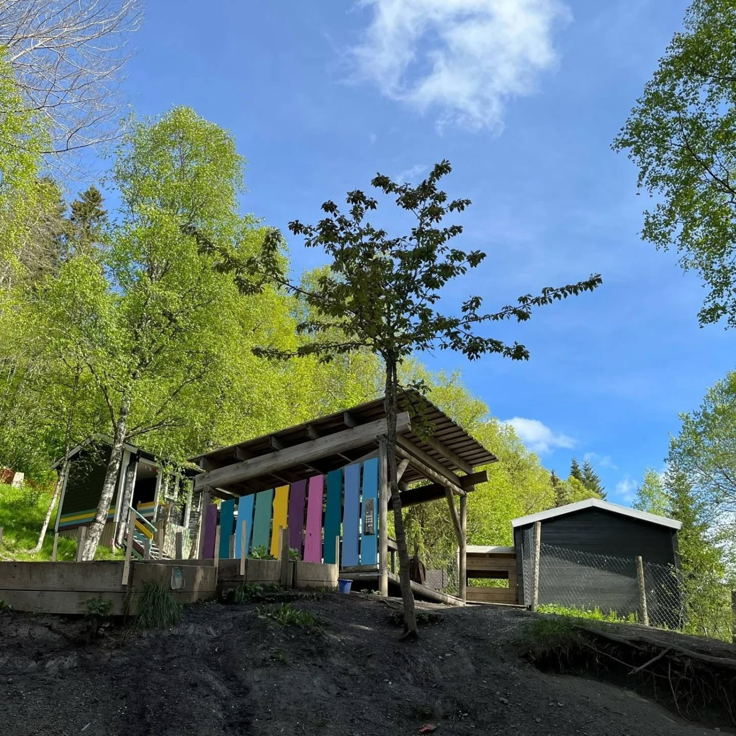 Naturlekeplassen Gulltopp med fargerik lekehytte under blå himmel